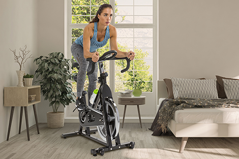 jongere-vrouw-op-spinningfiets-in-slaapkamer-in-sportieve-houding.jpg