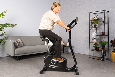 oudere-vrouw-op-hometrainer-in-woonkamer-rechtopzittend.jpg